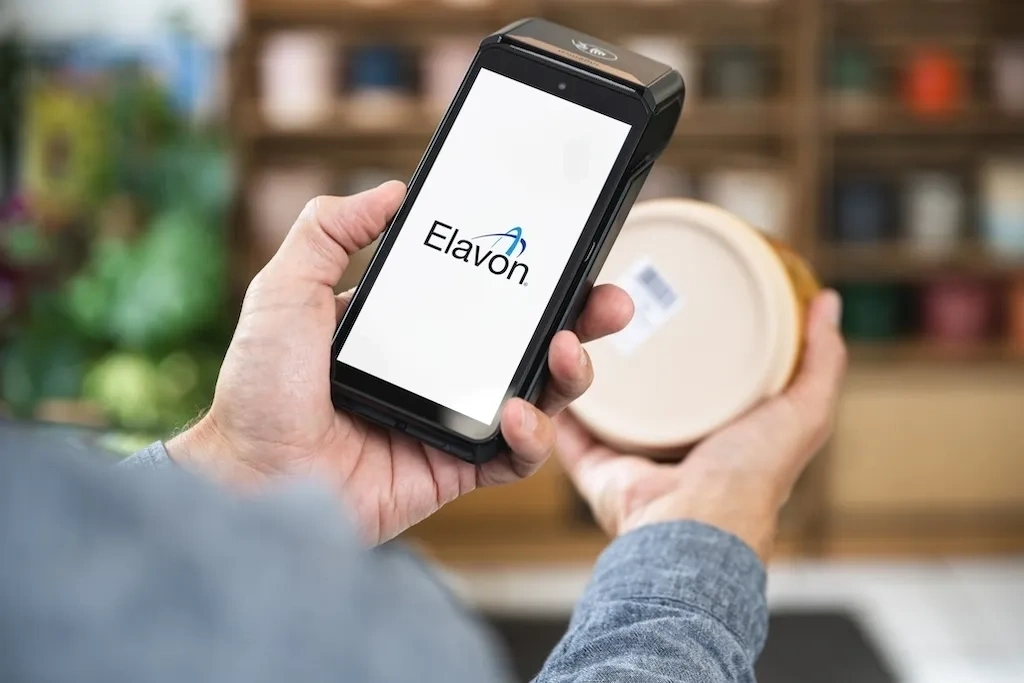 Person haelt zahlungsterminal und produkt mit barcode in einem geschaeft