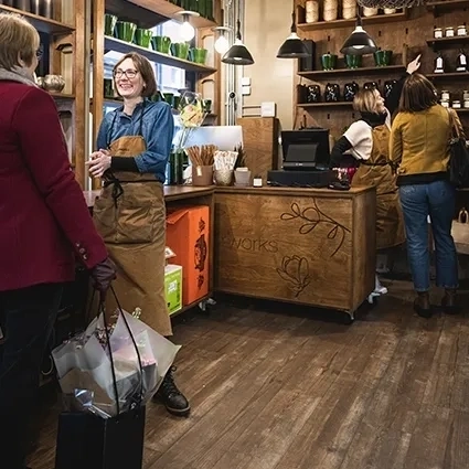 Einzelhandelsgeschäft mit kunden und mitarbeitern in der nähe der theke umgeben von regalen mit produkten